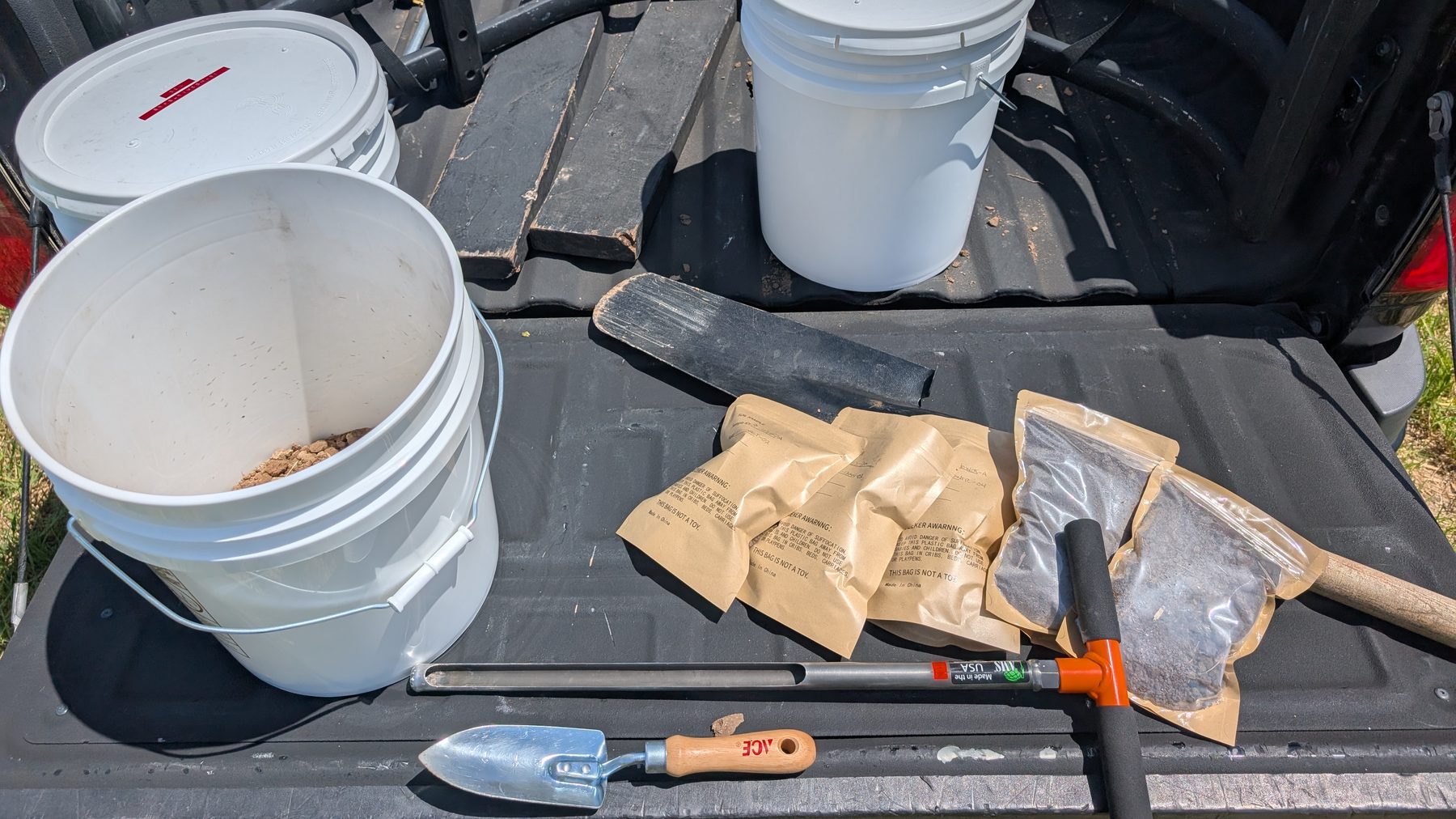 Soil sampling kit on the utility vehicle bed — buckets of gathered soil, labeled sample bags and hand tools