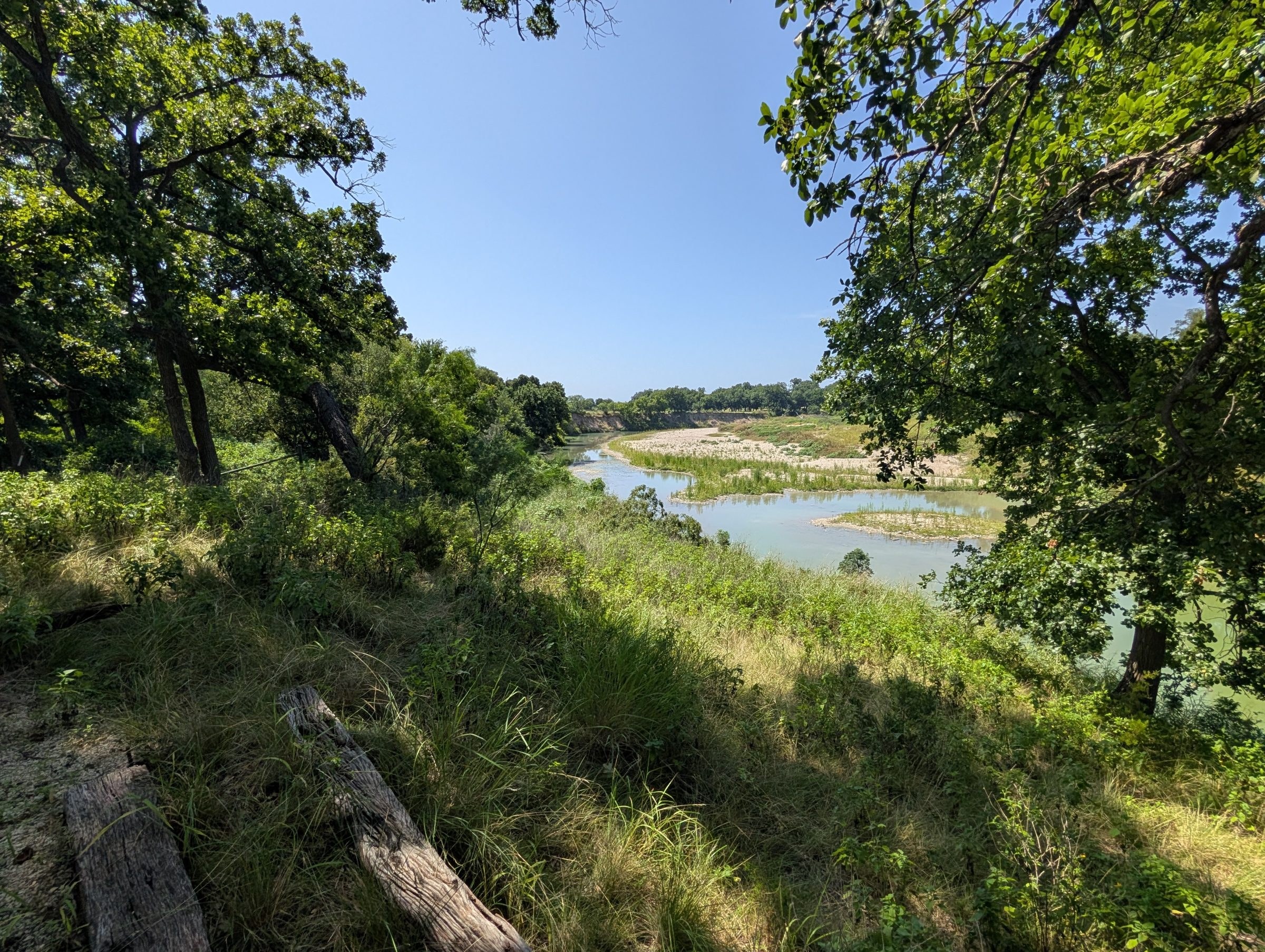 The Lampasas River bending past gravel bars below the property, seen through the oaks